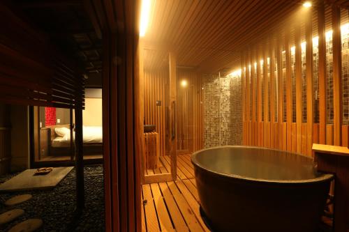 a bathroom with a tub in a room with a bed at Shoenso Hozugawatei in Kameoka