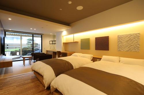 a hotel room with two beds and a dining room at Shoenso Hozugawatei in Kameoka