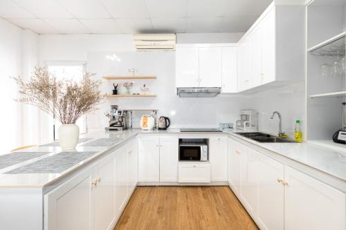 een witte keuken met witte kasten en een houten vloer bij Capital CauGiay Hotel in Hanoi