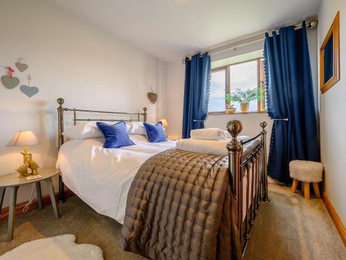 a bedroom with a bed and a window with blue curtains at Shepherds Cottage in Ambleside