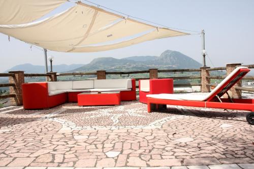 eine Terrasse mit roten und weißen Möbeln und einem Sonnenschirm in der Unterkunft DA LELLO - Bed & Relax in Torrecuso