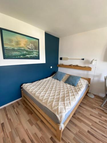 a bedroom with a bed and a blue wall at Apartament No. 2 in Łeba