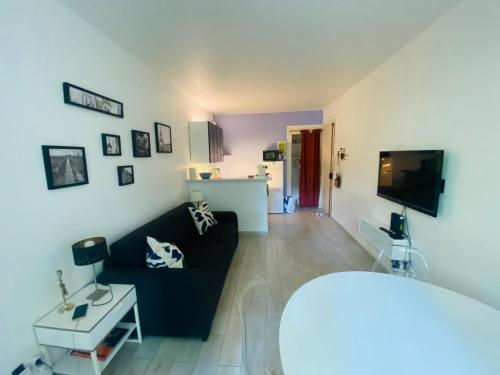 Una sala de estar con un sofá negro y un televisor. en Wendy family flat with calm courtyard 3min for metro Paris in 10 mins, en Maisons-Alfort