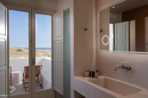 y baño con lavabo y espejo. en Acanthus Oia - Suites With Private Hot Tub, en Oia