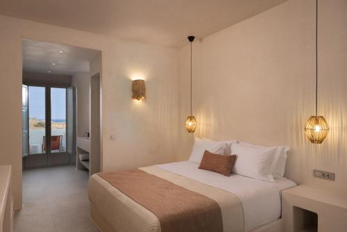 a bedroom with a bed with two lights on the wall at Acanthus Oia - Suites With Private Hot Tub in Oia