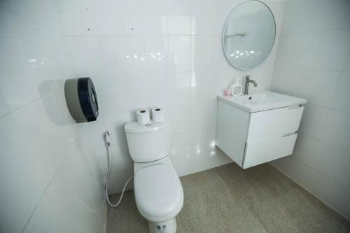 a white bathroom with a toilet and a sink at Oh'lala Studios in Ban Tai