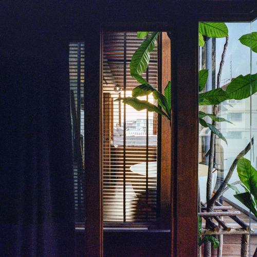 a window with wooden blinds and a plant in a room at Na Tanao 1969 in Bangkok