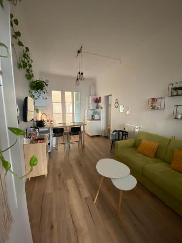 a living room with a green couch and a table at Appartement Proche plages - Parking gratuit in Menton