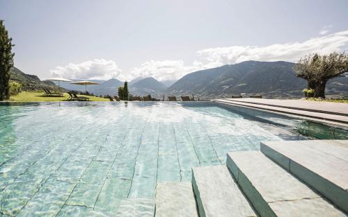 a large swimming pool with mountains in the background at Hotel Mitterplatt (Schenna Resort) in Schenna