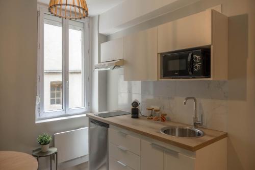 a kitchen with a sink and a microwave and a window at Bel appartement idéalement situé in Orléans