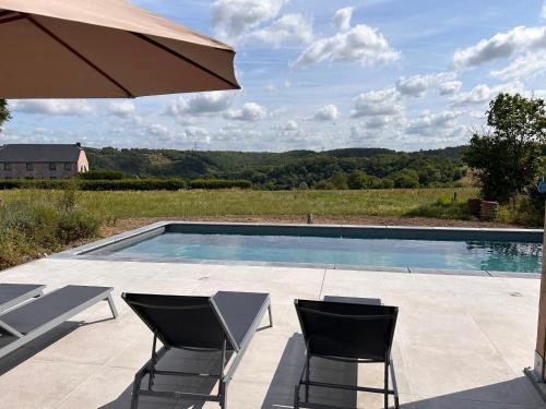 a swimming pool with two chairs and an umbrella at B&B Barvaux, Durbuy in Durbuy