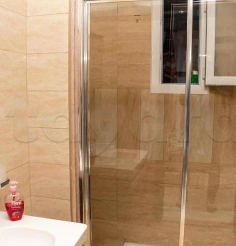 a shower with a glass door next to a sink at Front of sea with pool appartement in Sousse