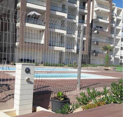 une clôture avec une piscine en face d'un bâtiment dans l'établissement Front of sea with pool appartement, à Sousse