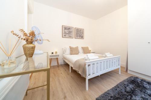a white bedroom with a bed and a glass table at Kensington luxury flat with patio in London