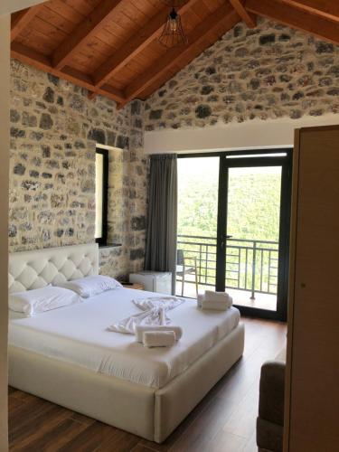 1 dormitorio con cama blanca y pared de piedra en Bujtina Vrenezi, en Peshkopi
