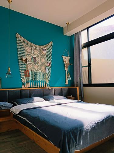 a bedroom with a large bed with a blue wall at 三田包棟旅宿MITA Inn in Tainan