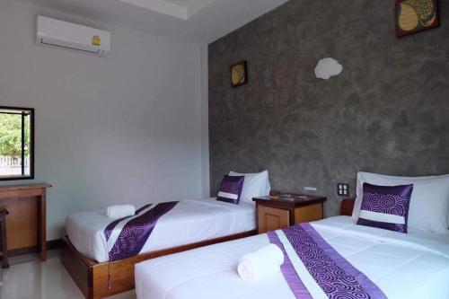 a bedroom with two beds with purple and white sheets at พูลสวัสดิ์ รีสอร์ท อ่าวมะนาว in Changwat Prachuap Khiri Khan