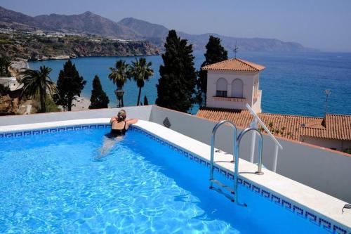 a woman in a swimming pool with a view of the ocean at Carabeillo Seaview Apartment in Nerja