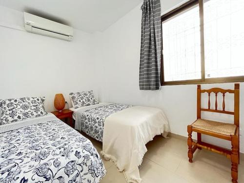 a bedroom with two beds and a chair and a window at Carabeillo Seaview Apartment in Nerja
