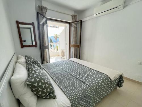 a bedroom with a bed with pillows and a window at Carabeillo Seaview Apartment in Nerja