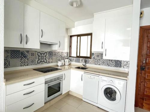 a kitchen with white cabinets and a washer and dryer at Carabeillo Seaview Apartment in Nerja