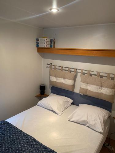 een bed met witte lakens en kussens in een kamer bij Charmant Mobil-home climatisé avec 2 chambres et entièrement équipé, sauf draps en option, pour 5 personnes au maximum in Sarlat-la-Canéda