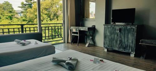 サムイ島にあるJALMIN Hotel Samuiのベッド2台、テレビ、バルコニーが備わる客室です。
