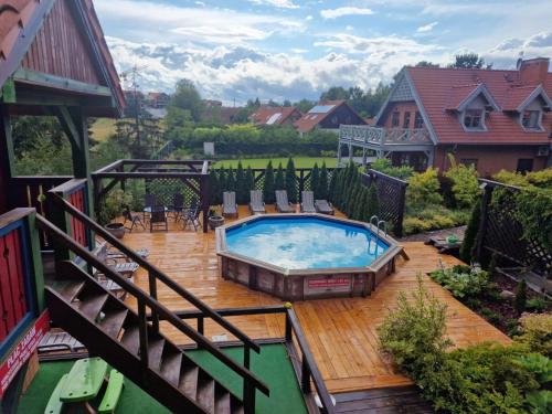 a swimming pool on a wooden deck with a house at DWÓR U PAPUGA in Ruciane-Nida