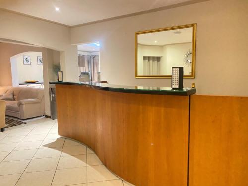 a reception desk in a hotel room with a mirror at Siena Sun Guesthouse Rooms and Breakfast Option in Midrand