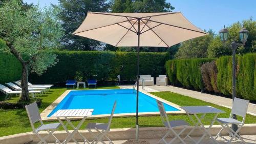 a pool with an umbrella and two chairs and a table and an umbrella at La Sorgente in Rocchetta a Volturno