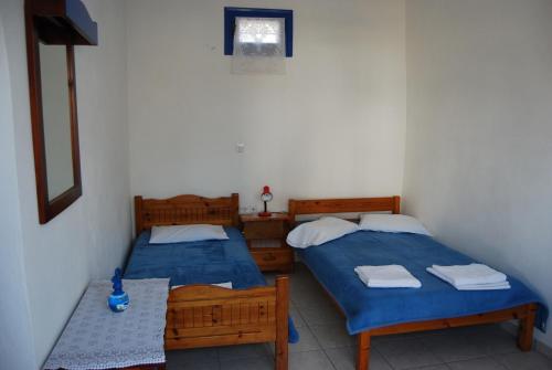 a room with two beds and a table and a window at Apollo Rooms in Perissa