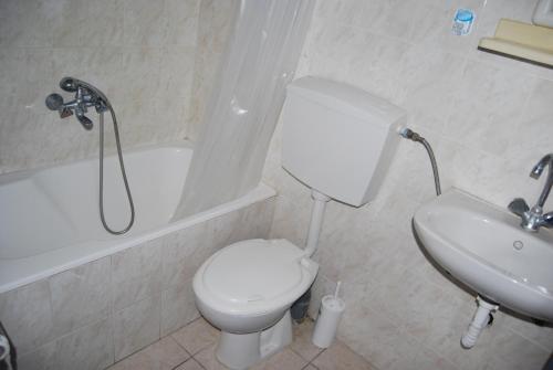 a bathroom with a white toilet and a sink at Apollo Rooms in Perissa