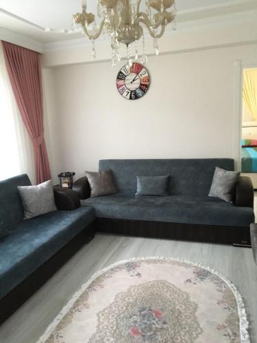 a living room with a couch and a clock on the wall at AYDIN APART. in Arsin