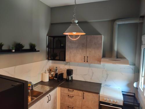 a kitchen with wooden cabinets and a pendant light at Deluxe Center Apartment - Preveza in Preveza