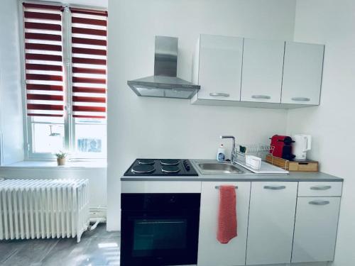 a white kitchen with a stove and a sink at Le Cocon de Sasha - Hyper Centre - FULL Climatisation - Proche Gare - 1 chambre - Canapé convertible - Géré par Presta-Zen'Services in Verdun