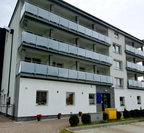 een appartementengebouw met balkons aan de zijkant bij Al-Dom Apartamenty, Apartament SUN w Welle z dostępem do sauny i jacuzzi in Grzybowo