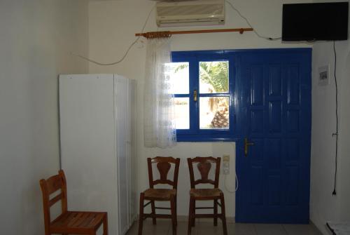 a room with two chairs and a blue door at Apollo Rooms in Perissa