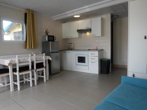 a kitchen with white cabinets and a table and chairs at Studio Bellevue in Égletons