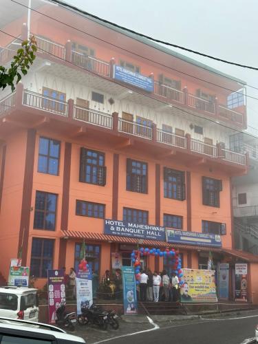 an orange building with people standing outside of it at Hotel Maheshwari & Banquet Hall in Tehri-Garhwāl