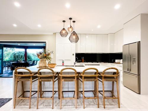 a kitchen with a table with chairs and a refrigerator at Hamilton House - Snowy Mountain Luxury Villas in Jindabyne