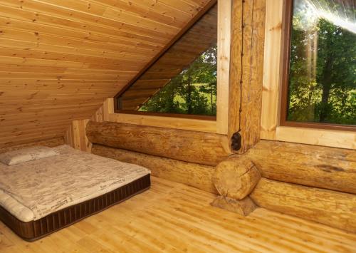 pokój z łóżkiem i oknem w drewnianym domku w obiekcie Pirtis pas Astą 