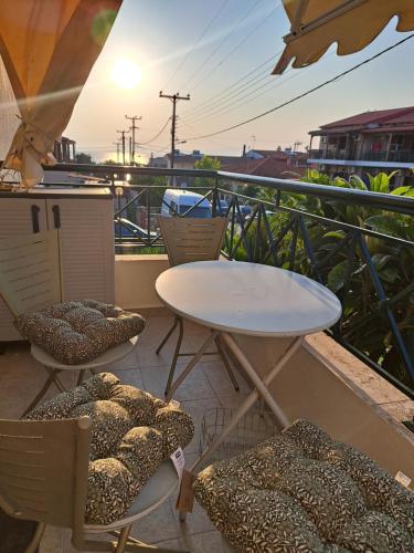 a table and chairs on a balcony with the sun setting at ART-appart sea view in Kallithea Halkidikis