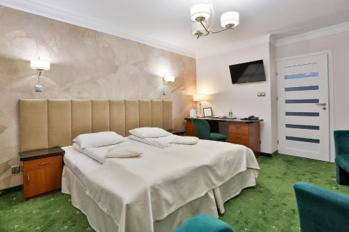 a bedroom with a bed and a desk and a television at Hotel Wiosna in Rabka
