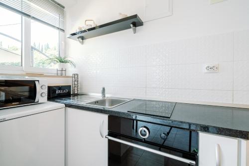 cocina con fregadero y microondas en Charming little apartment, en Čilipi