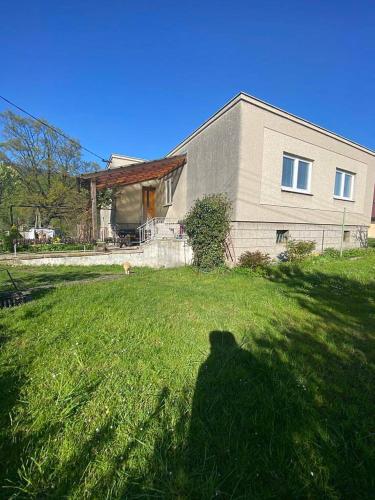 a shadow of a dog in the grass in front of a house at Domeček Pod horami in Raškovice