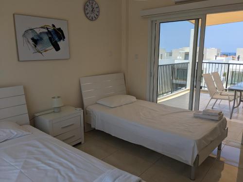 a bedroom with two beds and a balcony at Adalena Court in Paralimni