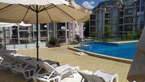 a pool with chairs and an umbrella next to a building at Kavarna Hills in Kavarna