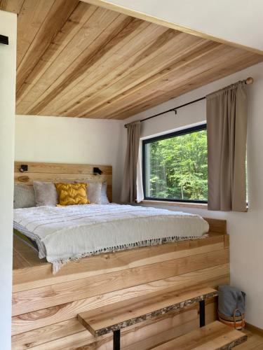 um quarto com uma grande cama de madeira e uma janela em Гірські будиночки em Zhdenievo