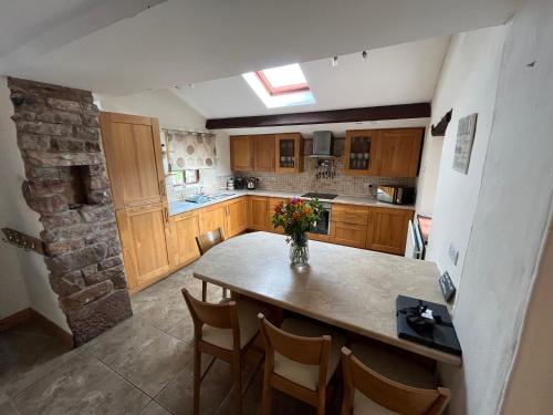 a kitchen with a table and chairs and a stone wall at The Cottage in Carlisle