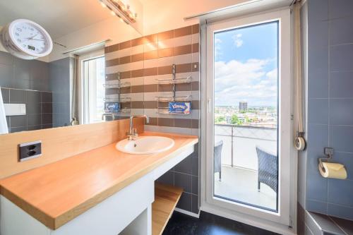a bathroom with a sink and a window with a view at City Dream Seeblick free parking in Kreuzlingen
